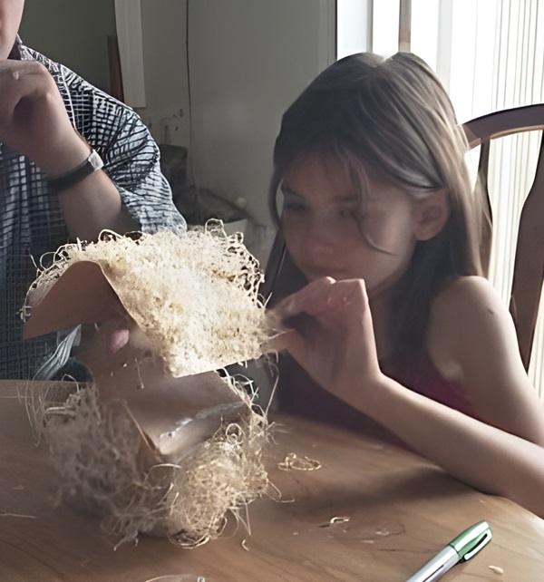 photo of a young girl putting the roof on her straw house
