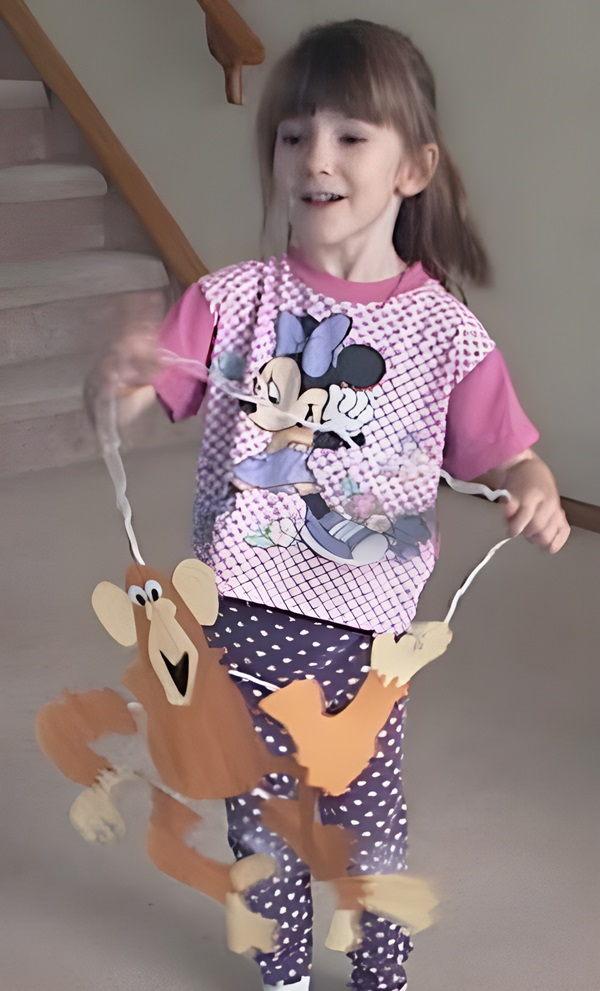 photo of a 6 year old girl playing with her the monkey puppet she made